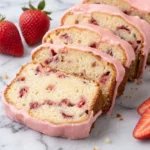 Slices of moist pound cake strawberries dessert with a pink glaze, served in a ceramic bowl with fresh strawberries nearby.